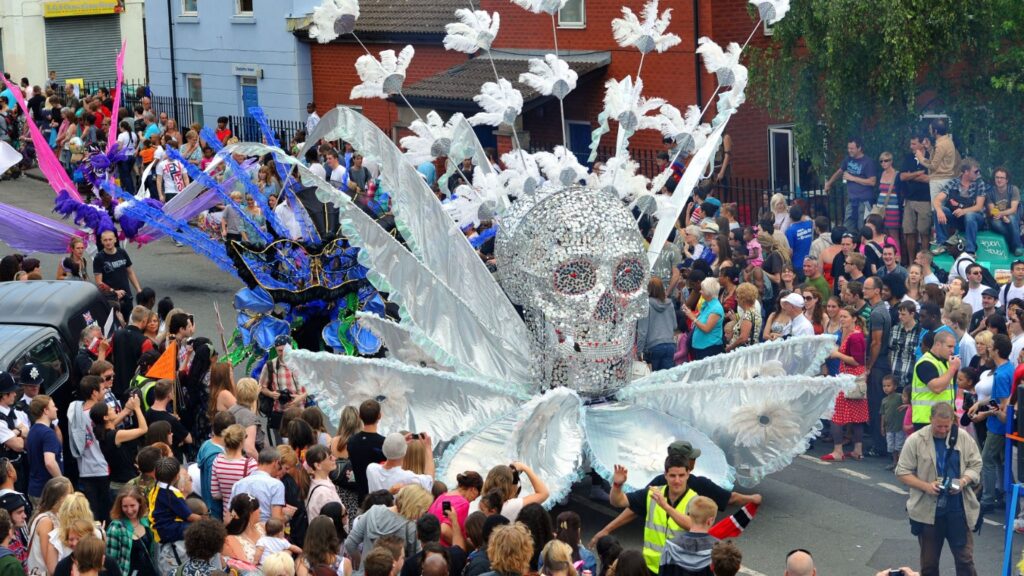 a crowd of people around a giant skull shaped carnicvl float decoration