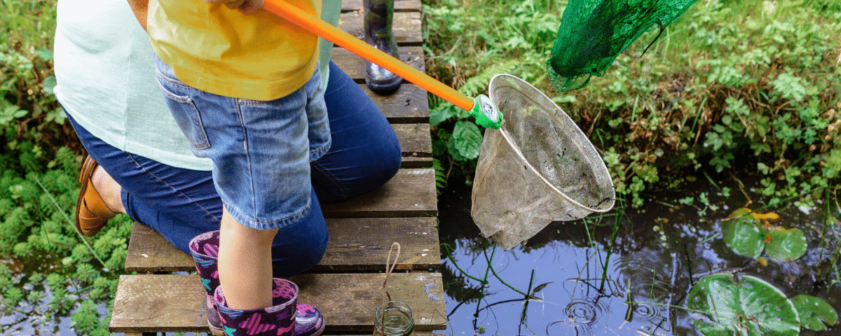 Image showing a child holding a net, standing next to a pond