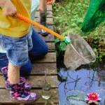 Image showing a child holding a net, standing next to a pond