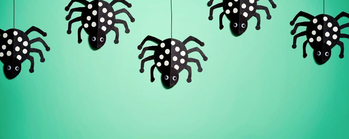 four black and white polka dot spiders hanging from strings