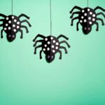 four black and white polka dot spiders hanging from strings
