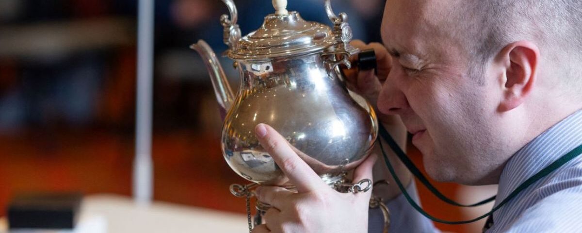 Image of a person looking at a silver teapot up close