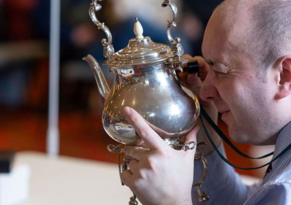 Image of a person looking at a silver teapot up close