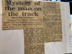 An old, yellowed newspaper clipping with torn edges features two columns of text. The main headline reads "Mystery of the man on the track," with a smaller headline "Recovered" above the second column. The article discusses a train tragedy and an inquest.